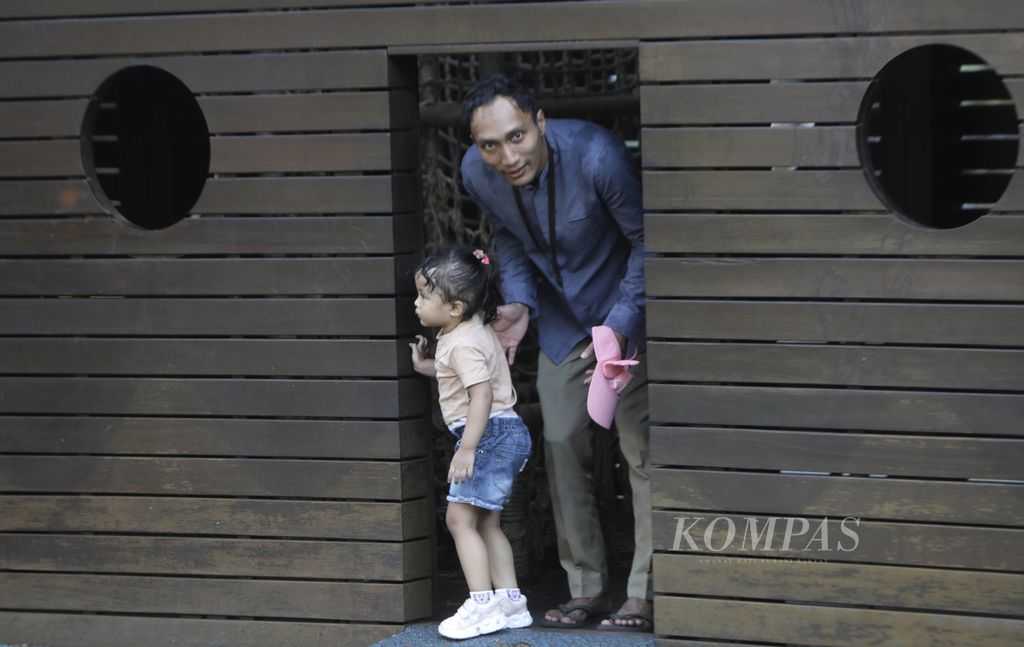 Seorang ayah menemani anaknya bermain di rumah-rumahan di taman bermain Tebet Eco Park, Jakarta Selatan, Kamis (21/3/2024).