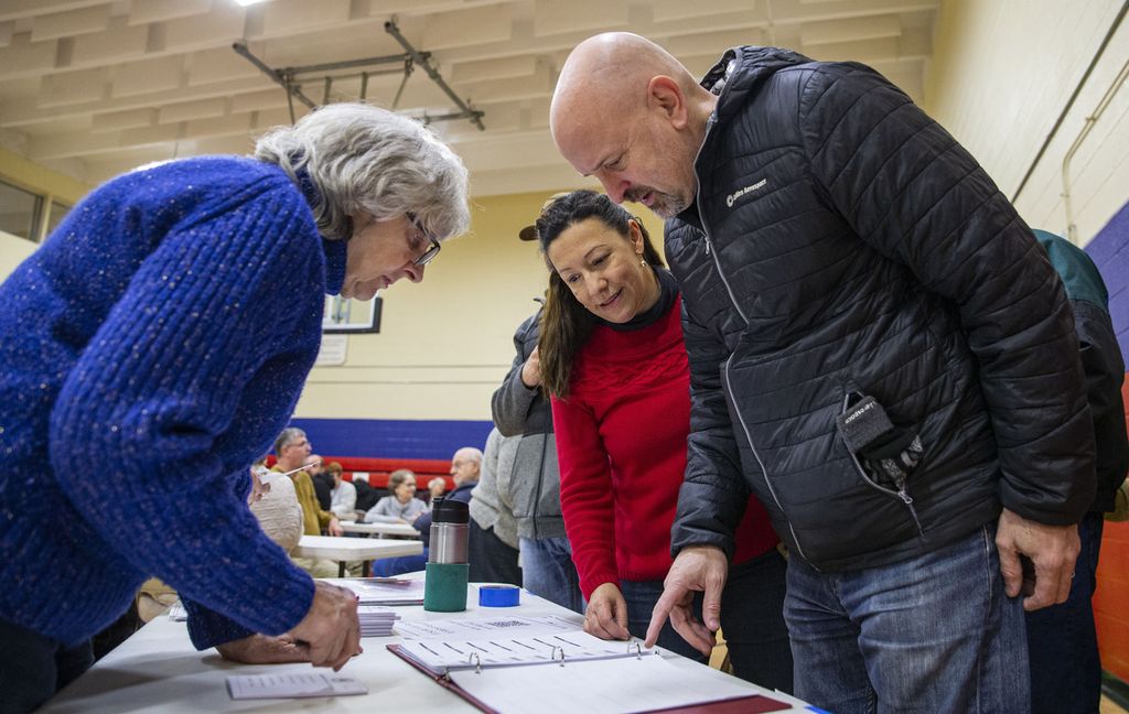 Sukarelawan Kaukus Partai Republik Iowa, Molly Seely (kiri), membantu para peserta untuk mendaftar jelang pemungutan suara di Cedar Rapids, Iowa, Senin (15/1/2024). 