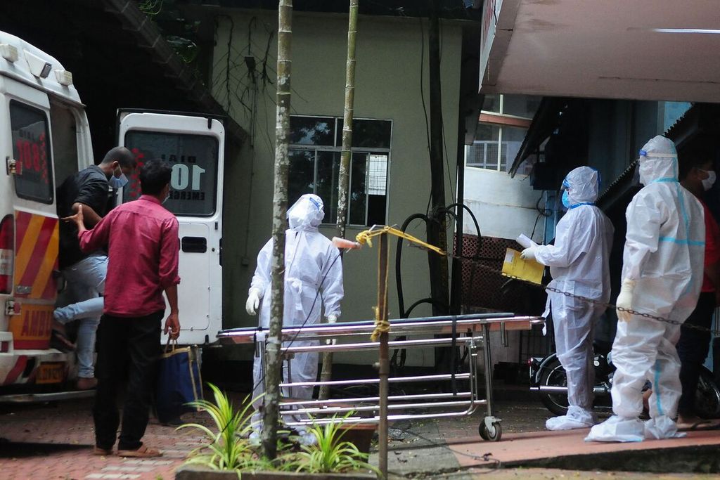 Petugas kesehatan, Selasa (12/9/2023), menggunakan alat pelindung diri atau <i>hazmat</i> saat membawa jenazah seorang terduga infeksi virus Nipah di sebuah rumah sakit diKozikode, Kerala, India.