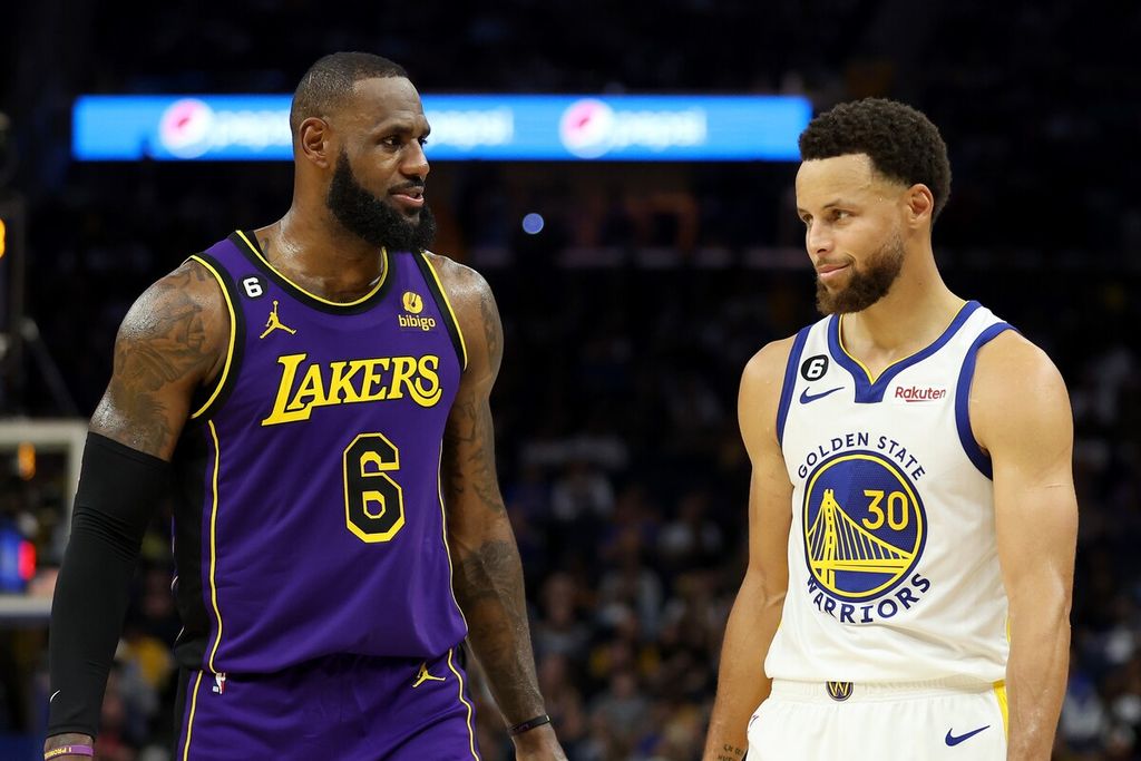 Pemain LA Lakers, LeBron James (kiri), dan pemain Golden State Warriors, Stephen Curry, berbincang saat pertandingan pembuka musim baru NBA antara LA Lakers dan Golden State Warriors di Chase Center, San Francisco, Rabu (19/10/2022) WIB.