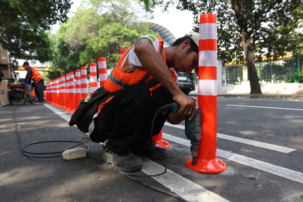 Seorang petugas memasang<i> stick cone </i>jalur sepeda di Jalan Tentara Pelajar, Kelurahan Gelora, Kecamatan Tanah Abang, Jakarta Pusat, Minggu (9/10/2022).