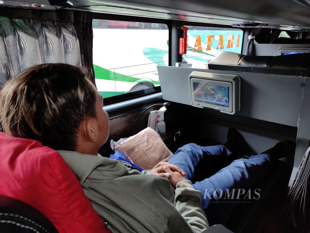 Penumpang bus <i>sleeper</i> Kencana menikmati tayangan televisi menjelang keberangkatan bus tersebut di Jakarta, Jumat (15/12/2023).