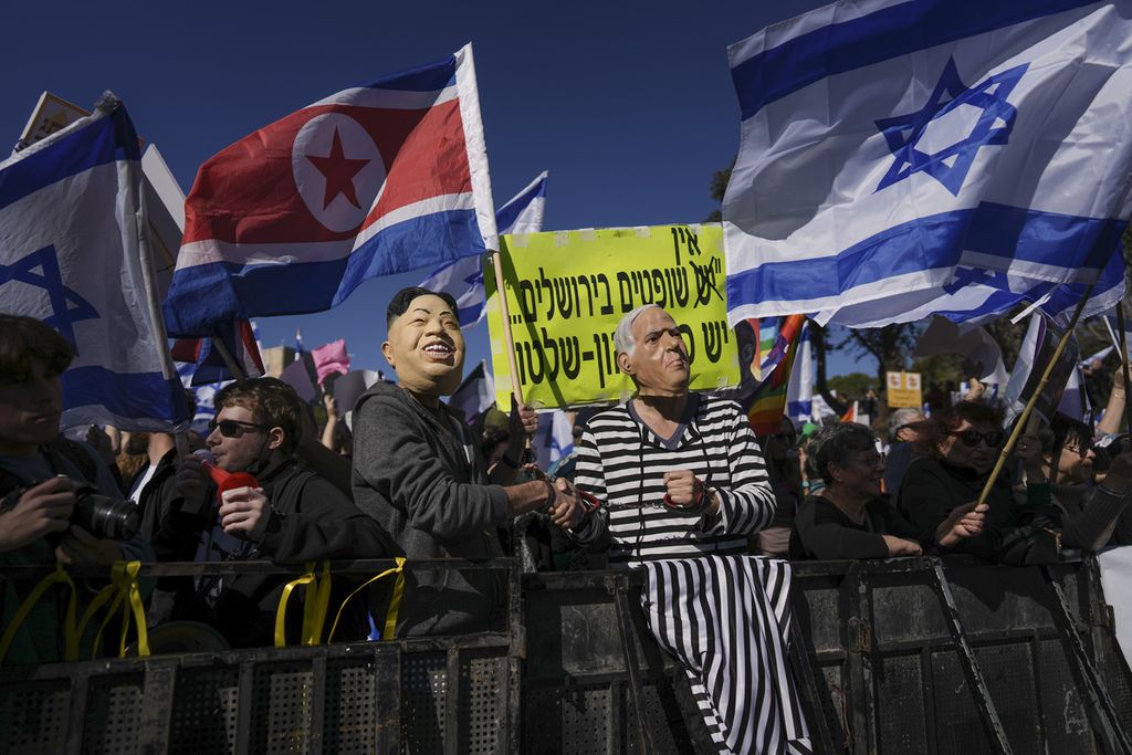 Pengunjuk rasa mengenakan topeng Perdana Menteri Israel Benjamin Netanyahu dan pemimpin Korea Utara Kim Jong Un dalam unjuk rasa  menentang pemerintahan baru yang dipimpin Netanyahu di depan parlemen Israel di Jerusalem, Kamis (29/12/2022). 
