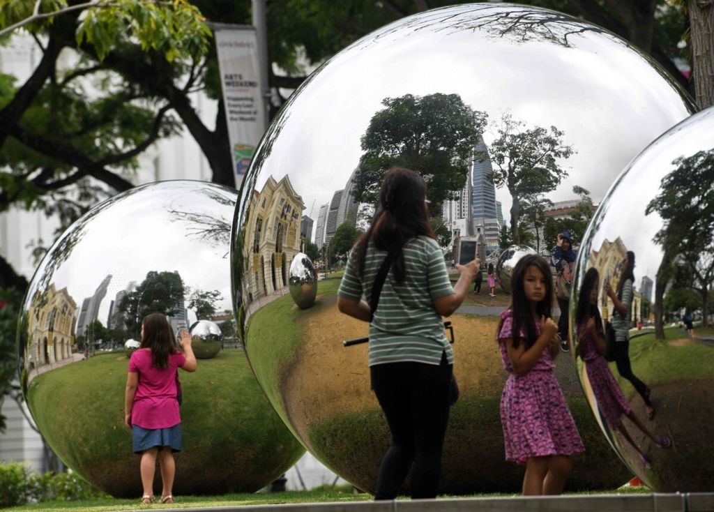 Anak-anak berdiri di sekitar instalasi seni reflektif di luar Asian Civilisations Museum di Singapura pada 19 Juni 2018.