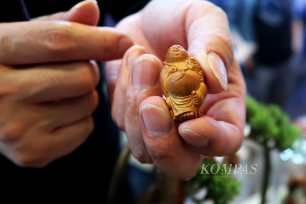 Seniman <i>hediao</i> atau seni ukir biji dan kacang asal Hunan, Ma Luo Cheng, memamerkan patung Buddha yang dibuatnya dari biji buah kepada pengunjung dalam acara jamuan makan malam World Tourism Cities Federation (WTCF) Changsha Fragrant Hills Tourism Summit 2023 di Changsha, Hunan, Selasa (9/5/2023). 