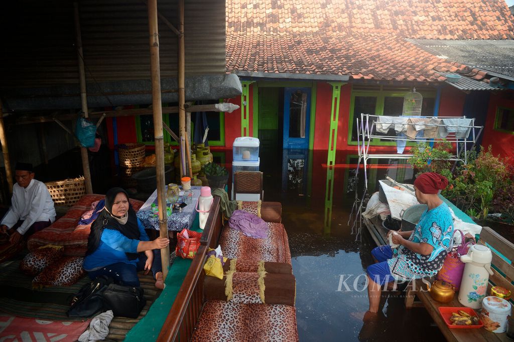 Warga yang mengungsi di halaman mereka yang lebih tinggi untuk menghindari banjir dari pasang air laut di Kampung Tirto, Kota Pekalongan, Jawa Tengah, Selasa (24/5/2022). Kondisi banjir rob ini merupakan yang terparah setelah jebolnya tanggul sungai hingga melimpas ke permukiman warga.  