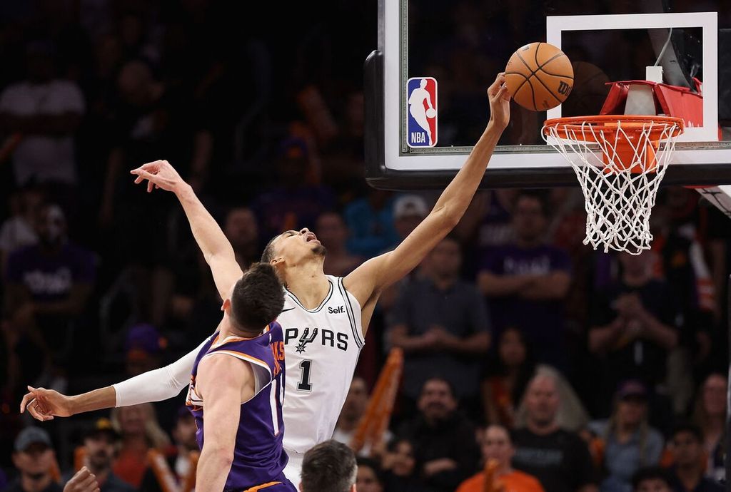 <i>Center </i>San Antonio Spurs, Victor Wembanyama, mencoba memasukkan bola melewati <i>forward </i>Phoenis Suns, Drew Eubanks, dalam pertandingan NBA antara Spurs dan Phoenix Suns di Footprint Center, Jumat (3/11/2023) WIB. Spurs mengalahkan Suns, 132-121.