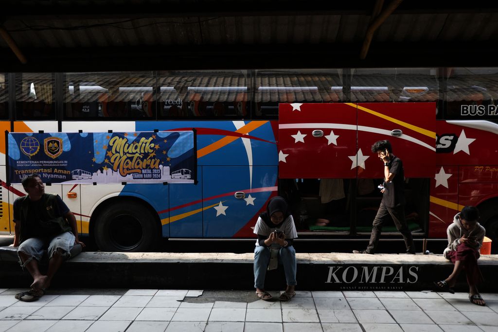 Warga melintas di depan bus yang terparkir di Terminal Kampung Rambutan, Jakarta, Sabtu (23/12/2023). 