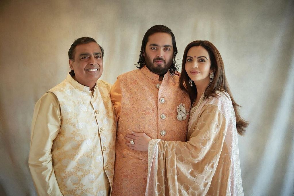 Miliarder India, Mukesh Ambani, dan istrinya, Nita Ambani, mengapit putra mereka, Anant Ambani, pada sesi foto, Sabtu (2/3/2024), dalam rangkaian pesta prapernikahan Anant Ambani dan Radhika Merchant di Jamnagar, India. 