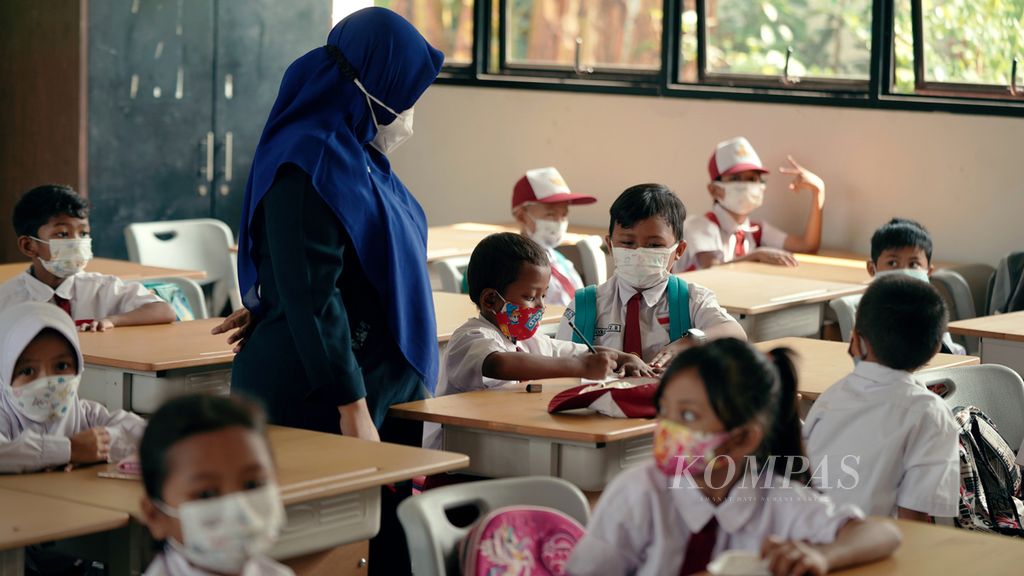 Guru memperhatikan pekerjaan anak didik dalam pembelajaran tatap muka (PTM) di SDN Klender 01, Jakarta Timur, Selasa (4/1/2022). 