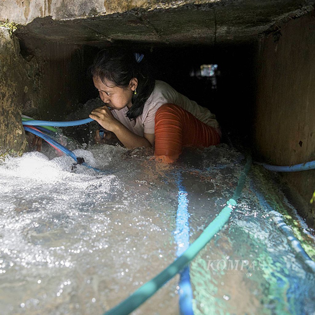 Ningsih (20) meniup selang saluran air yang terhubung ke rumahnya di bawah jembatan Dusun Kalidadap, Desa Selopamioro, Imogiri, Bantul, DI Yogyakarta, Selasa (21/3). Warga setempat menggunakan selang untuk mengalirkan air dari mata air ke rumah masing-masing.