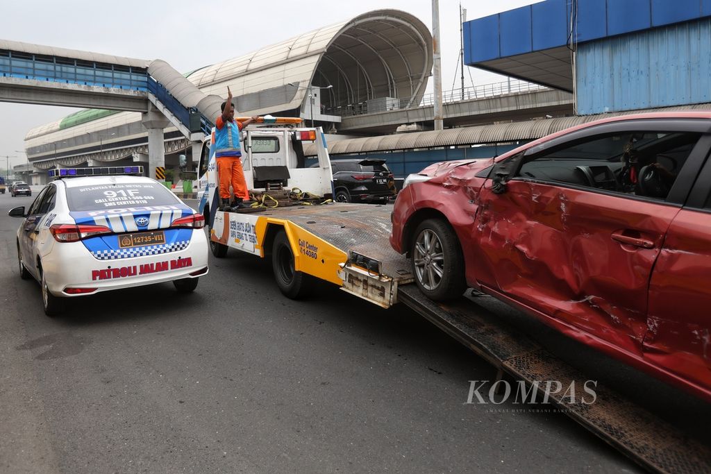 Petugas Jasa Marga mengarahkan mobil yang mengalami tabrakan saat diangkut di Gerbang Tol Halim Utama, Jakarta, Rabu (27/3/2024). 
