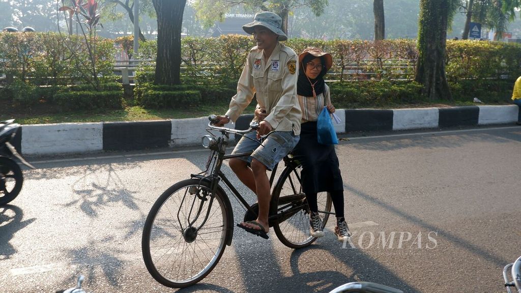 Seorang pegiat sepeda tua atau sepeda ontel membonceng pasangannya melewati Jalan Jenderal Sudirman, Kota Banjarmasin, Kalimantan Selatan, Minggu (24/9/2023). Para pegiat tetap menjaga budaya bersepeda ontel dan berupaya mewariskan budaya tersebut kepada generasi muda.