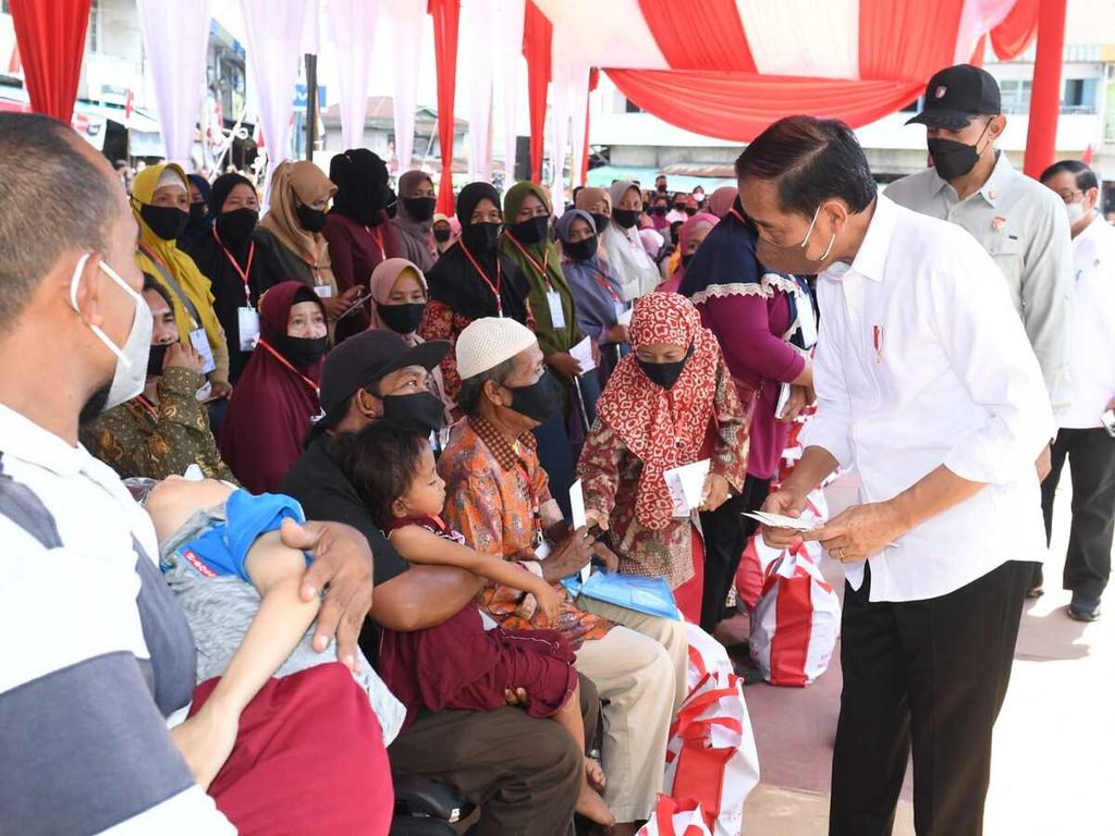 Presiden Joko Widodo didampingi Ibu Iriana Joko Widodo menyerahkan Bantuan Modal Kerja (BMK) dan Bantuan Langsung Tunai (BLT) minyak goreng kepada peserta Program Keluarga Harapan (PKH) di Pasar Sungai Duri, Kabupaten Bengkayang, Kalimantan Barat, Selasa (9/8/2022). 