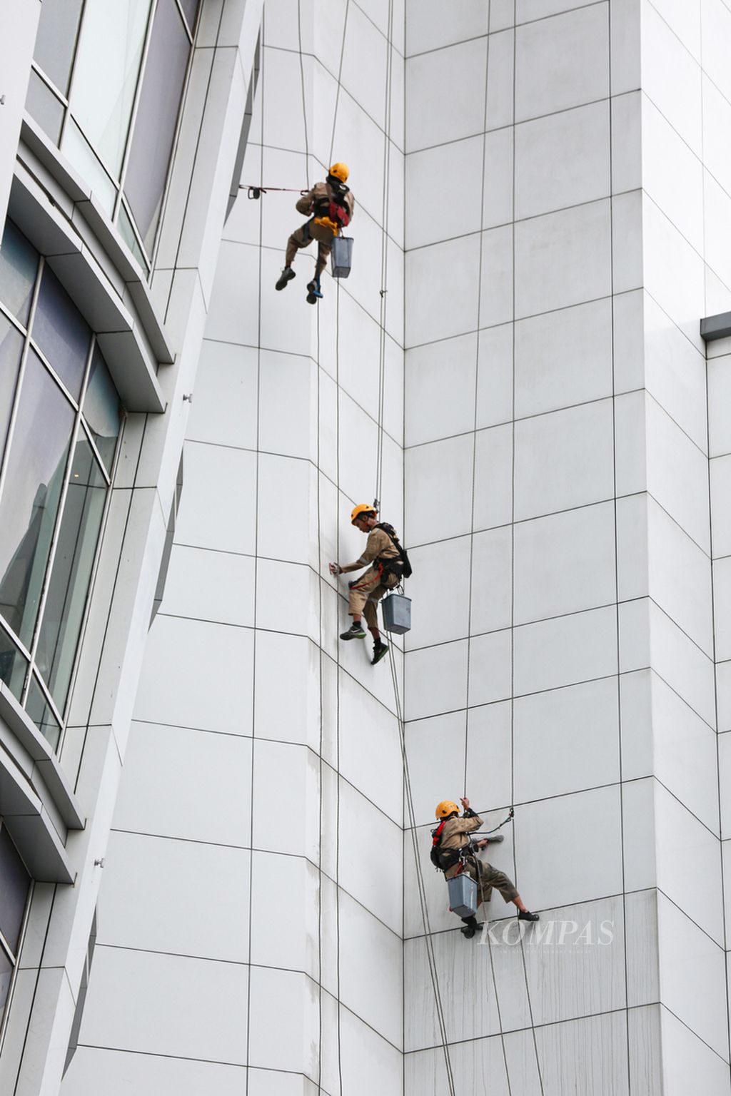 Workers hanging over to clean a shopping center building in the Senayan area, Central Jakarta, Tuesday (3/1/2023). Issuance of Government Regulation in Lieu of Law or Perppu Number 2 of 2022 concerning Job Creation is considered not to meet the critical requirements.