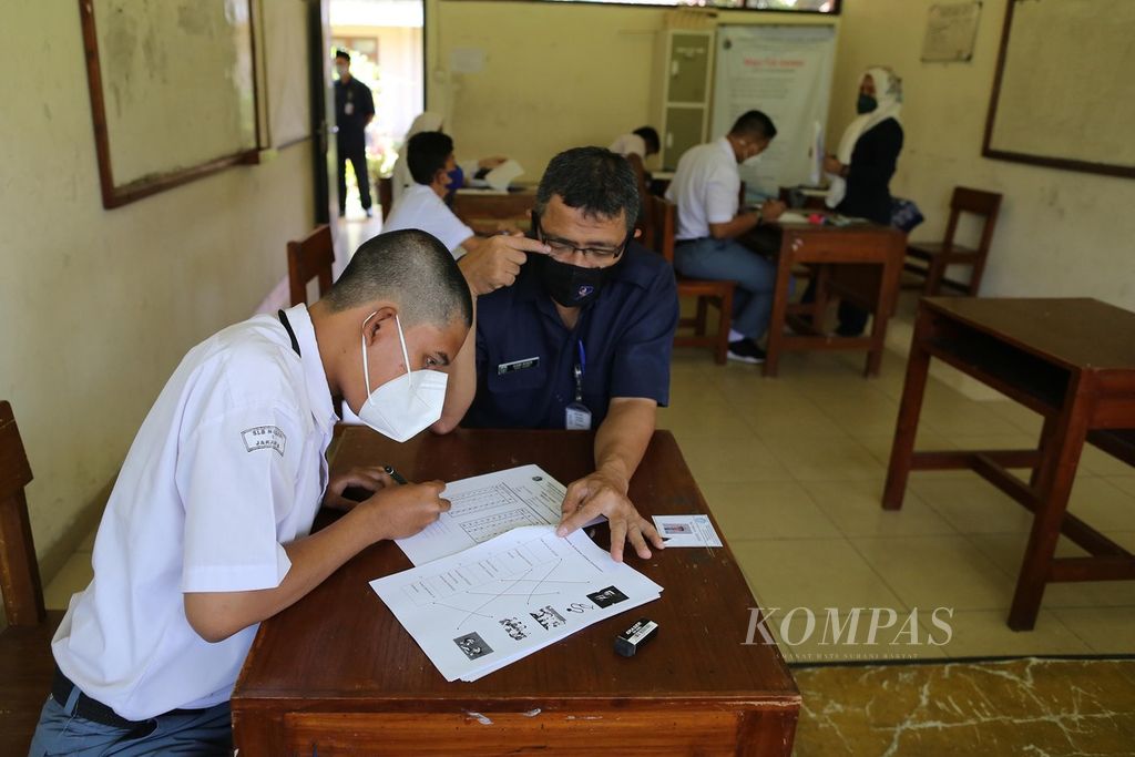 Guru pendamping membantu membacakan soal ujian saat siswa tunagrahita dari SMA SLB Negeri 1 Jakarta mengikuti ujian akhir sekolah, Senin (14/3/2022). 