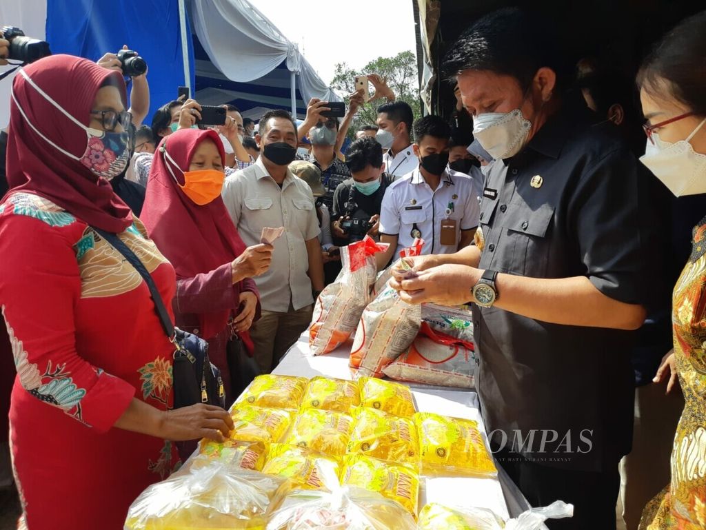 Gubernur Sumatera Selatan Herman Deru (kanan) menjual minyak goreng kemasan dalam operasi pasar di Pasar Alang-alang Lebar, Palembang, Sumatera Selatan, Kamis (12/1/2022). Operasi pasar ini dilakukan untuk menstabilkan harga minyak goreng yang dalam dua bulan terakhir meningkat hingga Rp 21.000 per liter.