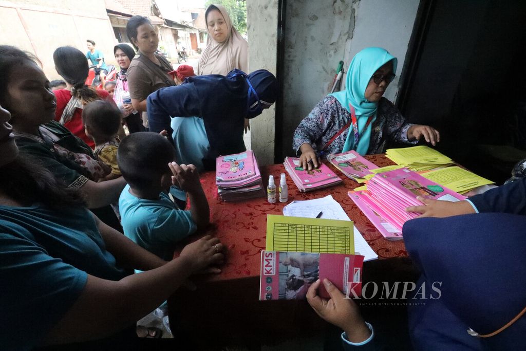 Petugas kader posyandu melayani pendaftaran ibu-ibu yang berkunjung untuk pemeriksaan rutin anak-anak mereka di Posyandu RW 05 Rawa Terate, Cakung, Jakarta Timur , Selasa (14/2/2023). Pembagian gizi tambahan diberikan untuk mengurangi prevalensi tengkes. Pemerintah menargetkan anak usia balita bebas dari tengkes pada 2030. 