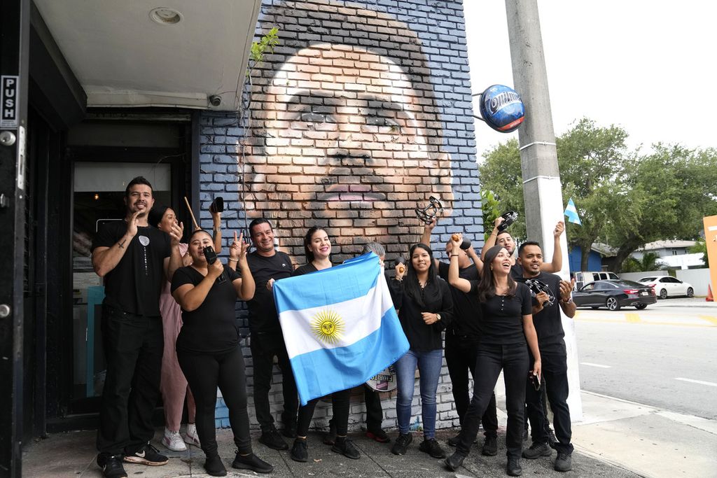 Para pekerja Restoran Fiorito di Miami, Florida, berfoto dengan bendera Argentina dan mural wajah Lionel Messi, Rabu (7/6/2023), setelah Messi memastikan untuk bergabung dengan klub Inter Miami di Liga Sepak Bola Mayor (MLS) Amerika Serikat. 