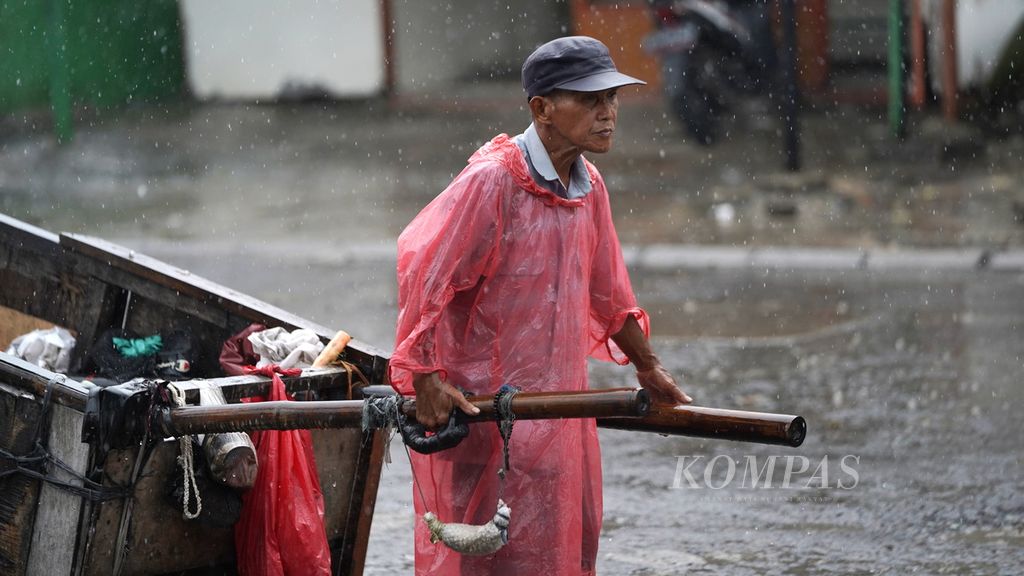 Scavengers penetrate the rain on Pondok Ungu Permai Street, Happy Village, Babelan District, Bekasi Regency, West Java, Tuesday (14/3/2023). For some ordinary people, life has been able to eat a day, it has made them feel happy.