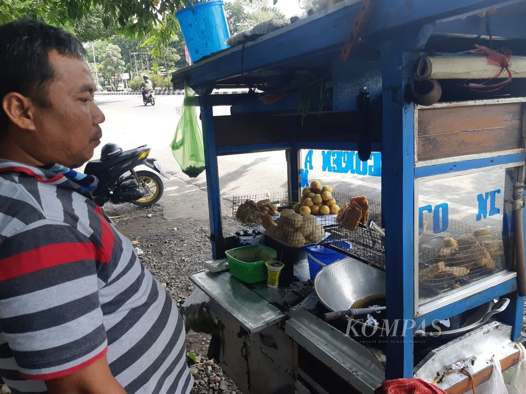 Sahidin (48) menggoreng adonan tempe dan tahu di gerobaknya di Jalan Brigjen Dharsono, Kota Cirebon, Jawa Barat, Selasa (8/3/2022). Sahidin mengeluhkan harga minyak goreng curah yang mencapai Rp 18.000 per liter, naik dibandingkan biasanya yang Rp 11.000 per liter.