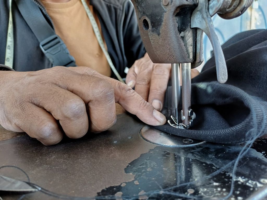 Agus Sopian (45) is sewing one of his customer's pants at his roadside stall in Pasar Kosambi, Kota Bandung, West Java, on Sunday (24/3/2024).