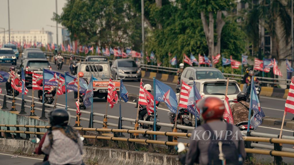Warga melintasi bendera Partai Demokrat dan Partai Kebangkitan Nusantara di kawasan Kampung Melayu, Jakarta Timur, Rabu (14/9/2022). 