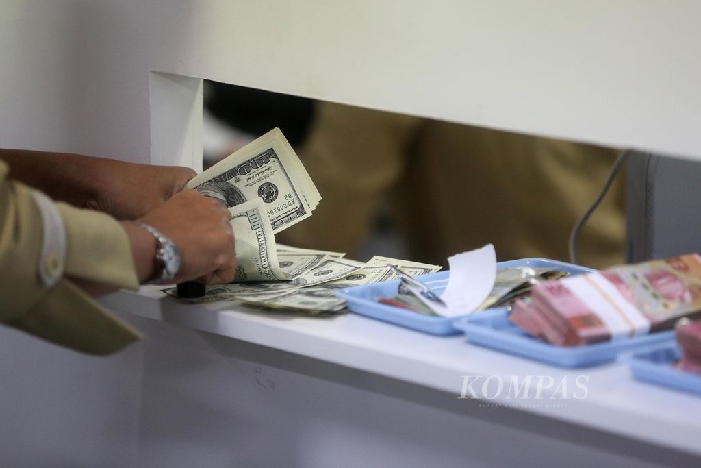 Petugas menghitung uang dollar AS di tempat penukaran valuta asing PT Ayu Masagung di Jakarta, Februari 2020. 