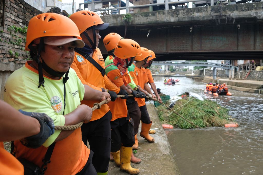 Petugas Prasarana dan Sarana Umum serta Unit Pelaksana Kebersihan Badan Air menarik tumpukan sampah di bantaran Kali Ciliwung, Jakarta Pusat, Kamis (10/11/2022). 