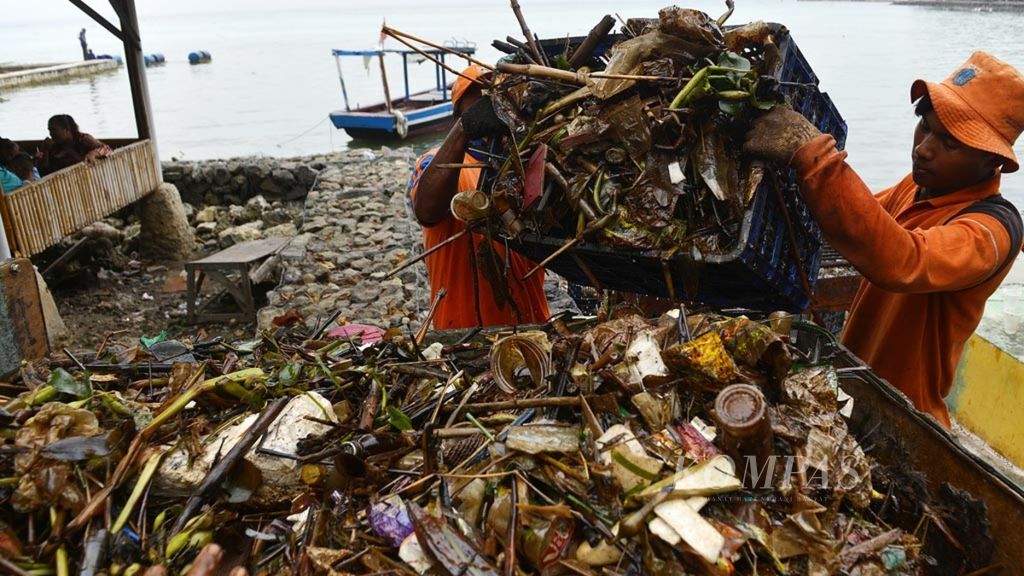 Petugas dari Suku Dinas Lingkungan Hidup Kepulauan Seribu membersihkan sampah di pantai di Pulau Pari, Kepulauan Seribu, Jakata, Jumat (30/11/2018). Sampah yang hanyut sampai ke pantai tersebut sebagian besar berlumur limbah minyak.
