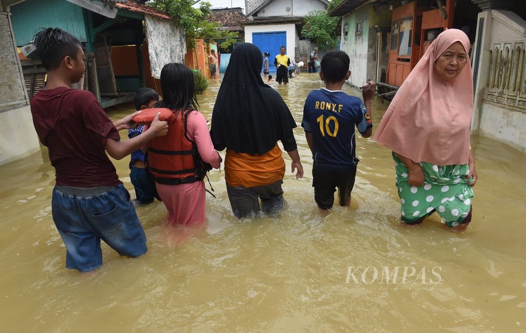 Warga menerjang banjir di Jalan Kenari, Kecamatan Sampang, Kabupaten Sampang, Jawa Timur, Senin (2/1/2023). 