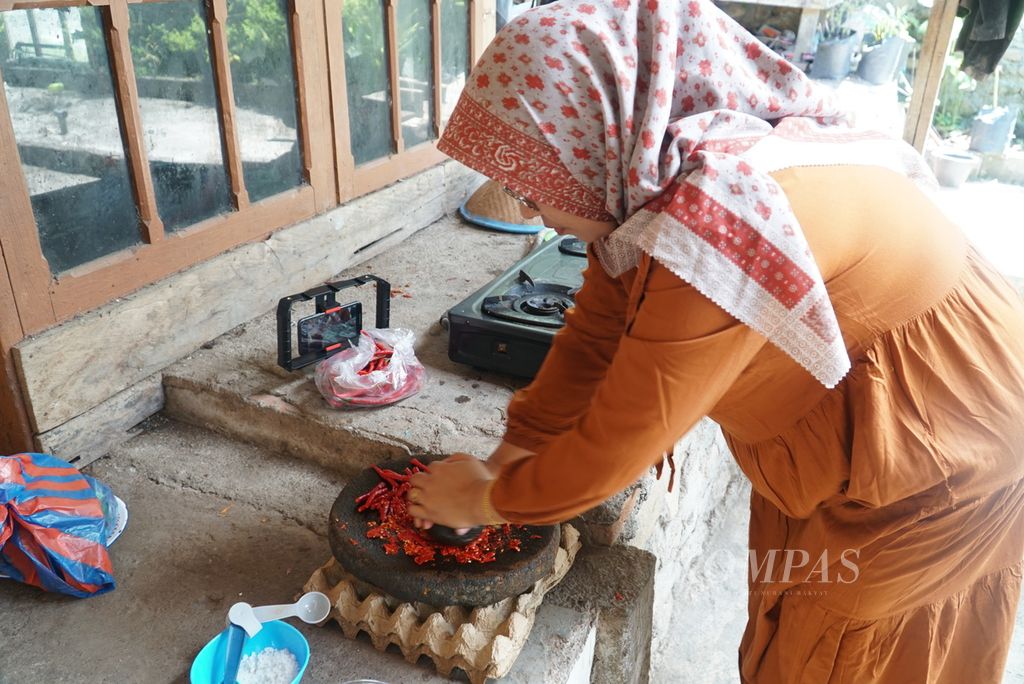 Warga menggiling cabai merah untuk membuat samba lado tulang di Nagari Parambahan, Kecamatan Limo Kaum, Tanah Datar, Sumatera Barat, Jumat (27/5/2022). Samba lado tulang adalah makanan khas masyarakat Tanah Datar.