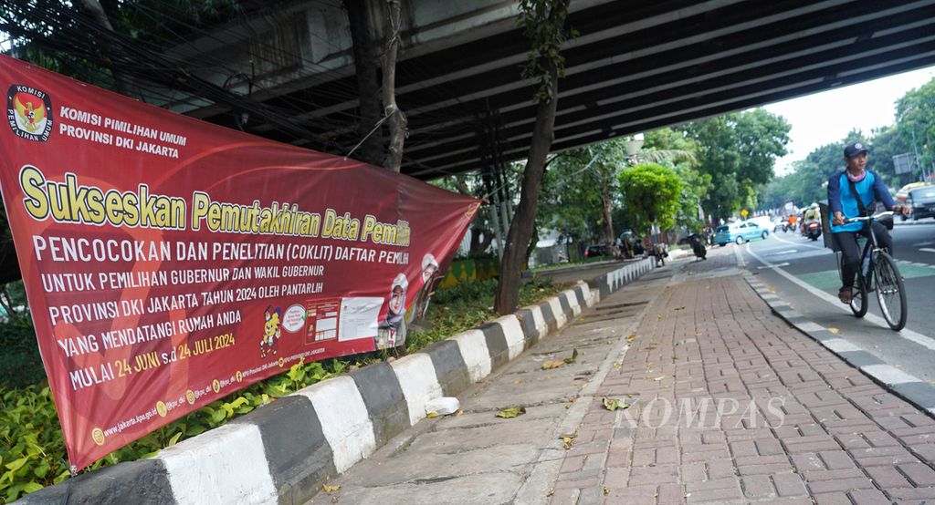 Pesepeda melewati jalan yang terdapat spanduk sosialisasi pencocokan dan penelitian (coklit) data kependudukan menjelang pilkada serentak 2024 yang terpasang di Jalan Dr Saharjo, Jakarta, Minggu (21/7/2024). Pelaksanaan coklit data kependudukan oleh Panitia Pendaftar Pemilih 2024 dari setiap wilayah Panitia Pemungutan Suara ini akan segera berakhir pada Rabu (24/7/2024).