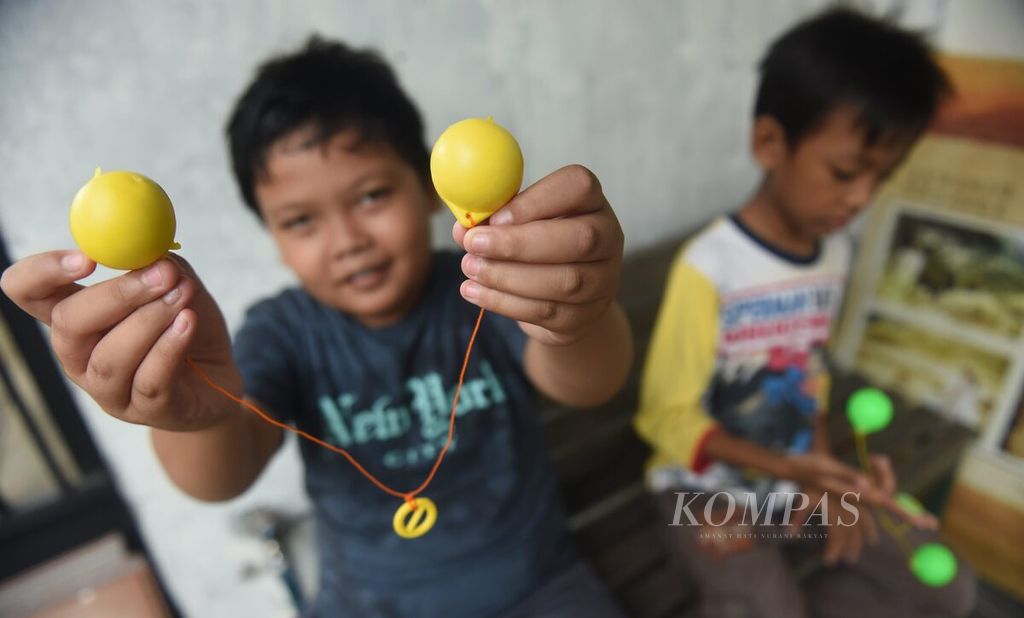 Seorang anak menunjukkan lato-lato miliknya di salah satu kompleks perumahan, Kecamatan Sukodono, Kabupaten Sidoarjo, Jawa Timur, Senin (26/12/2022). Permainan tradisional tersebut kini kembali tren setelah lama hilang tergantikan oleh permainan modern.