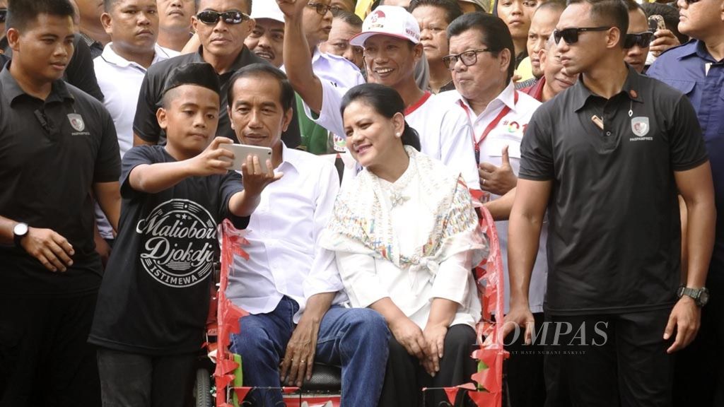 Joko Widodo, bersama Nyonya Iriana menumpang becak menuju lokasi kampanye terbuka di Lapangan Ahmad Kirang, Mamuju, Sulawesi Barat, Kamis (28/3/2019). Tak hanya menyapa, keduanya juga melayani warga yang ingin berswafoto bersama.