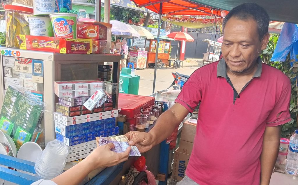 Juni, pedagang toko kelontong di Palmerah Selatan, Jakarta, saat menerima uang dari pelanggannya, Rabu (7/6/2023).