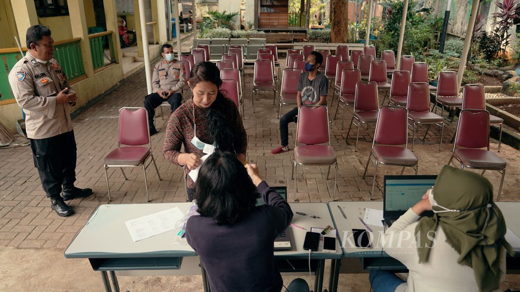 Warga menyiapkan dokumen sebelum menjalani vaksinasi penguat di halaman Kelurahan Duren Sawit, Jakarta Timur, Minggu (12/6/2022). Sebanyak 100 vaksin disiapkan oleh tenaga kesehatan dari Puskesmas Duren Sawit dan Polsek Duren Sawit. Vaksinasi penguat yang melayani kedatangan langsung tersebut mulai pukul 08.00 hingga 12.00 . Data vaksinasi nasional per tanggal 11 Juni 2022 pukul 18.00 dari Kementerian Kesehatan menyebutkan total vaksinasi dosis pertama  200,831,652 dosis (96.43 persen), total vaksinasi dosis kedua 168,047,214 dosis (80.69 persen), dan total vaksinasi dosis ketiga 45,591,835 dosis (22.85 persen). 