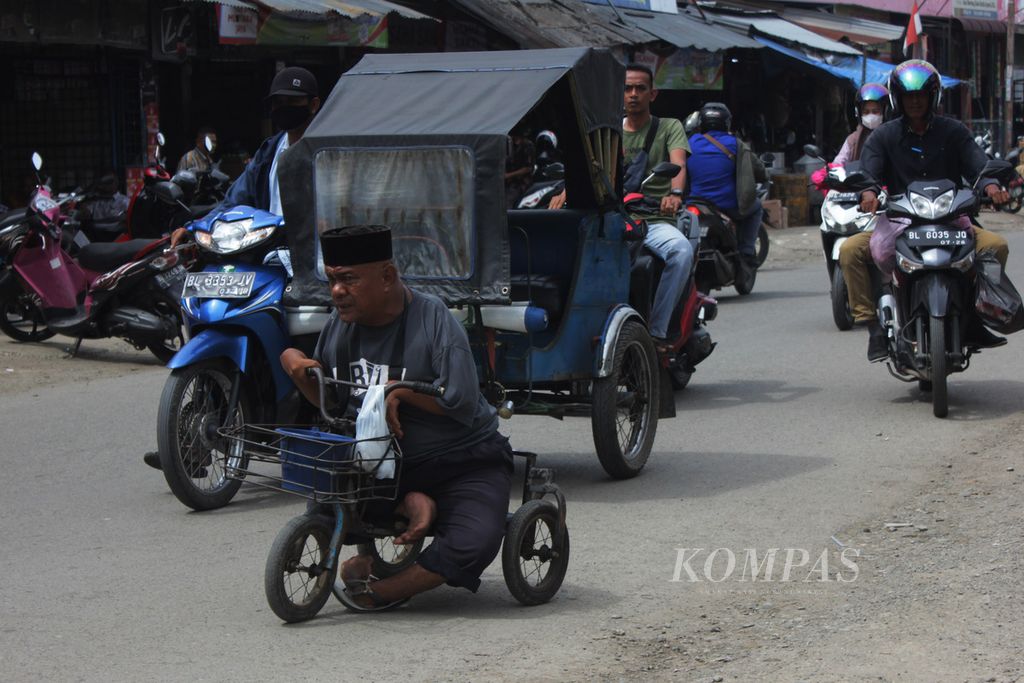 Muhammad Nasir (44), penyandang disabilitas, mengayuh sepeda yang telah dimodifikasi menyusuri jalan di Pasar Lambaro, Kabupaten Aceh Besar, Provinsi Aceh, Kamis (17/3/2022). Lapangan pekerjaan untuk penyandang disabilitas dan perlindungan sosial masih minim.