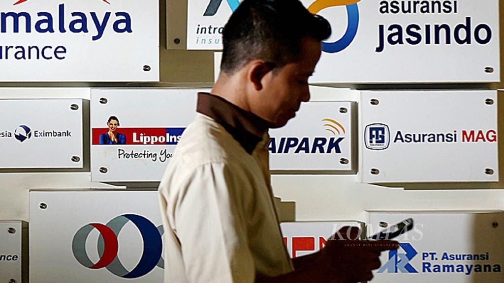 Karyawan melintas di papan nama-nama perusahaan asuransi di kantor Asosiasi Asuransi Umum Indonesia di Jakarta, Senin (5/3/2018).