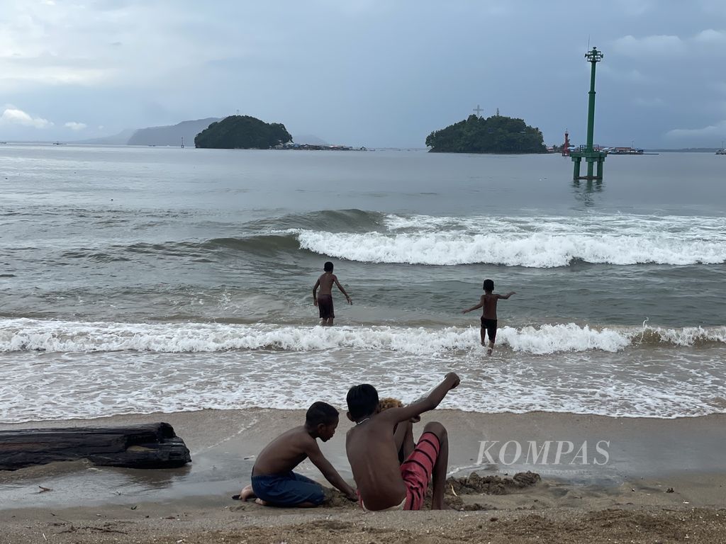 Anak-anak bermain di pantai di kawasan pesisir Kota Jayapura, Papua, Jumat (19/12/2023).