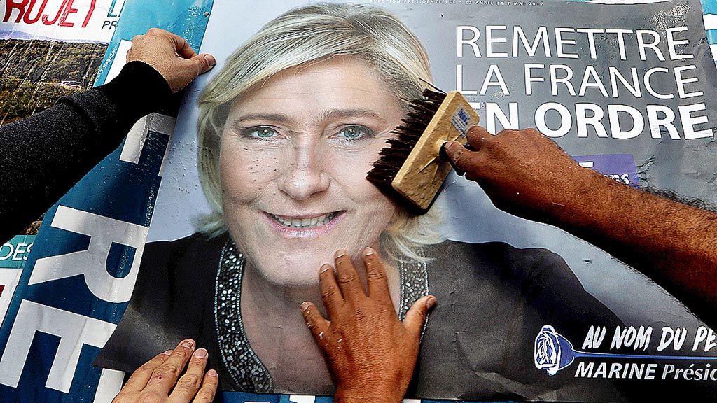 Para anggota partai Front Nasional Perancis menempel poster yang menampilkan gambar pemimpin partai tersebut, Marine Le Pen, dalam rangkaian kampanye pemilihan presiden, di Antibes, Perancis, Jumat (14/4).   