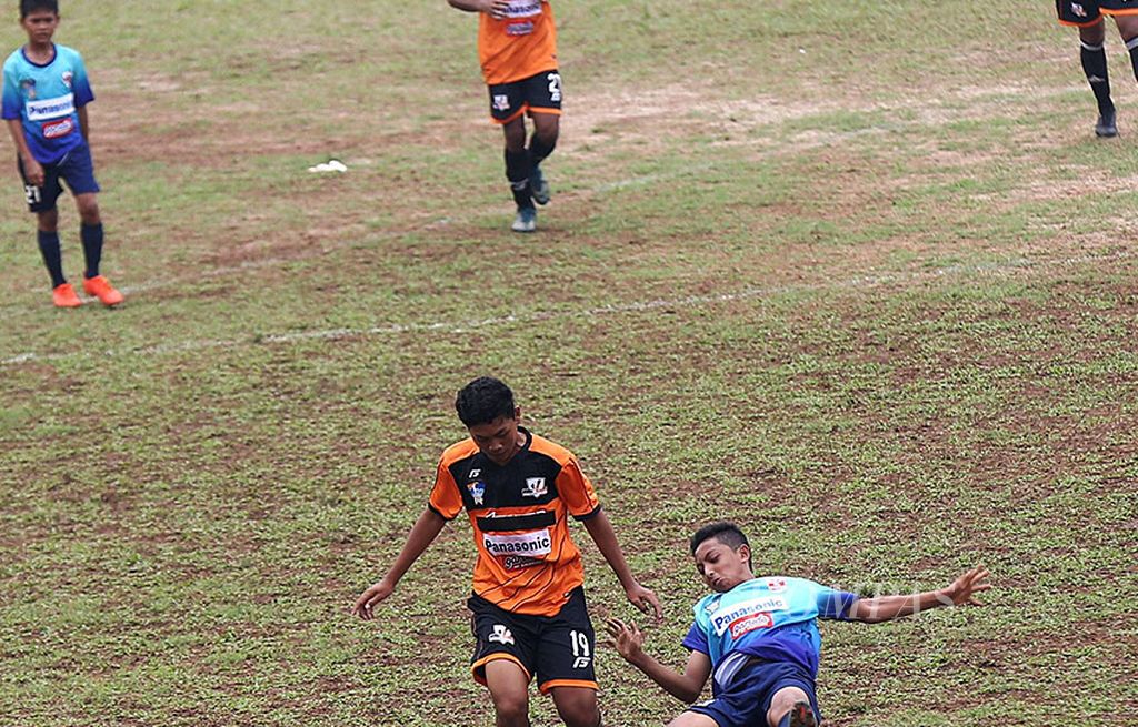 Pemain SSB Ragunan Soccer School, Muhammad Ihsan Setiadi (kanan), terjatuh saat berebut bola dengan pemain SSB Villa 2000, Gibran Dewata Sujana, pada pekan pertama Liga Kompas Gramedia Panasonic U-14 di Stadion GOR Ciracas, Jakarta Timur, Minggu (13/8). SSB Villa 2000 menang 1-0.