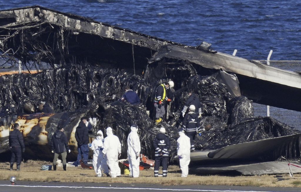 Para petugas menyelidiki bangkai pesawat Japan Airlines di Bandara Haneda, Kamis (4/1/2024). 