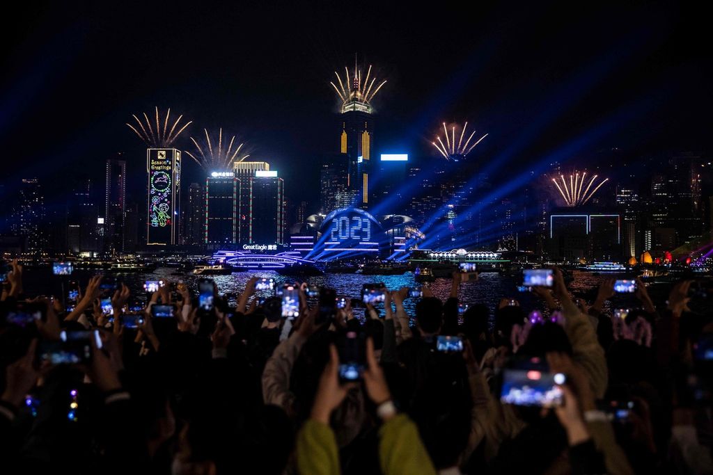 Warga merekam pesta kembang api dan laser pada malam perayaan Tahun Baru dengan perangkat gawai masing-masing di dekat Victoria Harbour, Hong Kong, Minggu (1/1/2023).