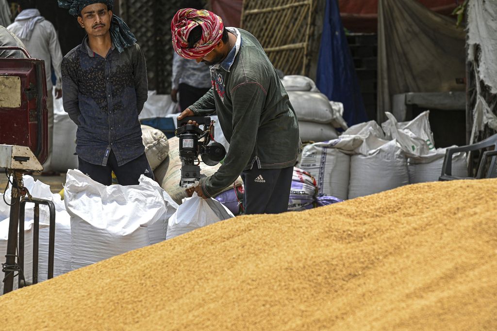Pekerja menjahit karung berisi gandum di sebuah pasar di Ghaziabad, Negara Bagian Uttar Pradesh, India, Selasa (17/5/2022). 