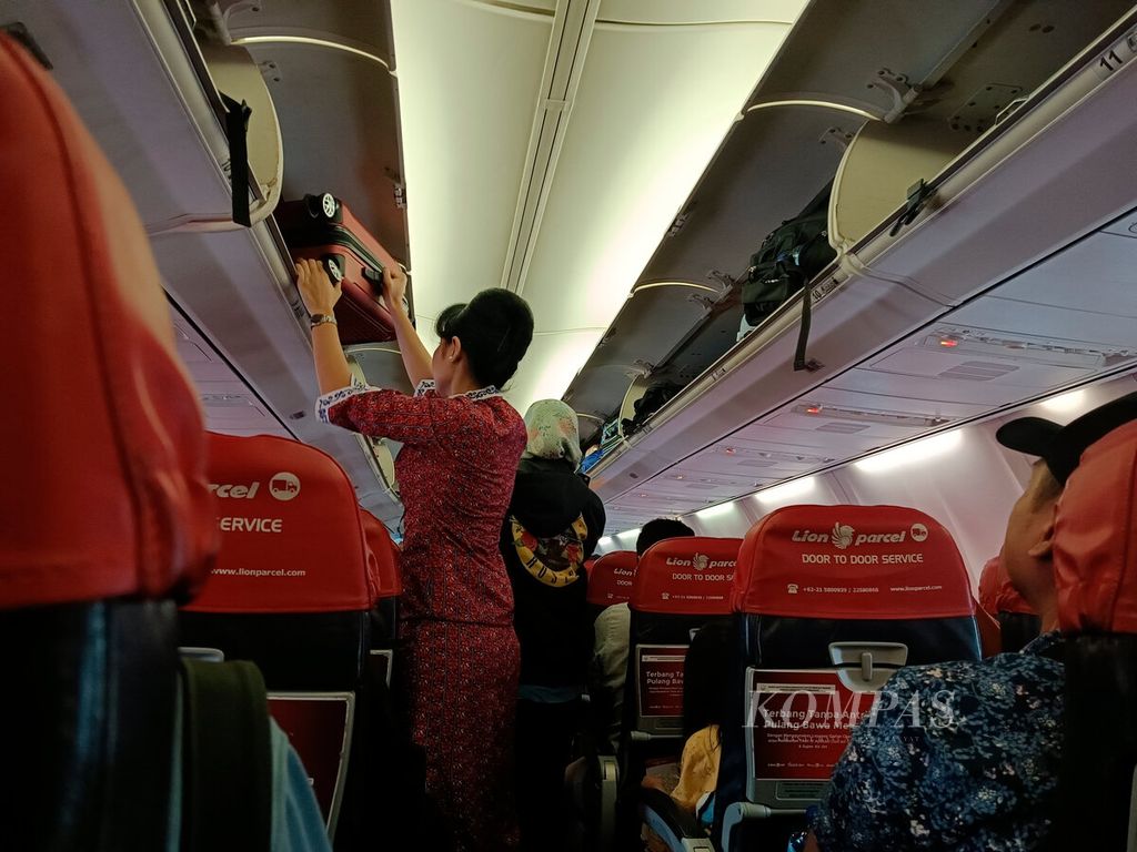 Pramugari membantu merapikan tas penumpang pesawat sesaat sebelum tinggal landas di Bandara Internasional Ahmad Yani, Kota Semarang, Jawa Tengah, Selasa (20/6/2023). 