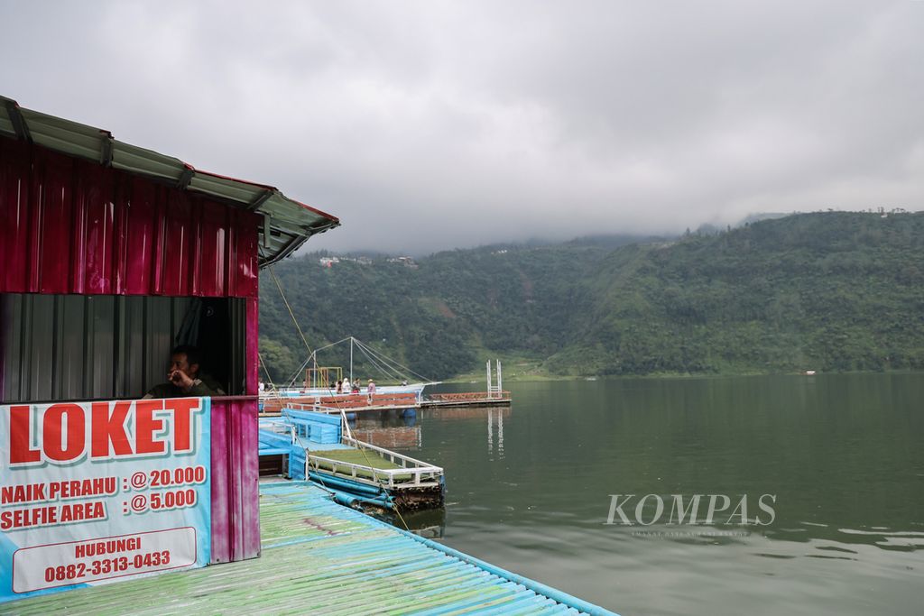 Petugas menanti wisatawan di Telaga Menjer di Desa Maron, Garung, Kabupaten Wonosobo, Jawa Tengah, Kamis (11/4/2024). Selain untuk wisata, air dari telaga terluas di Dataran Tinggi Dieng ini juga dimanfaatkan untuk pembangkit listrik tenaga air. 