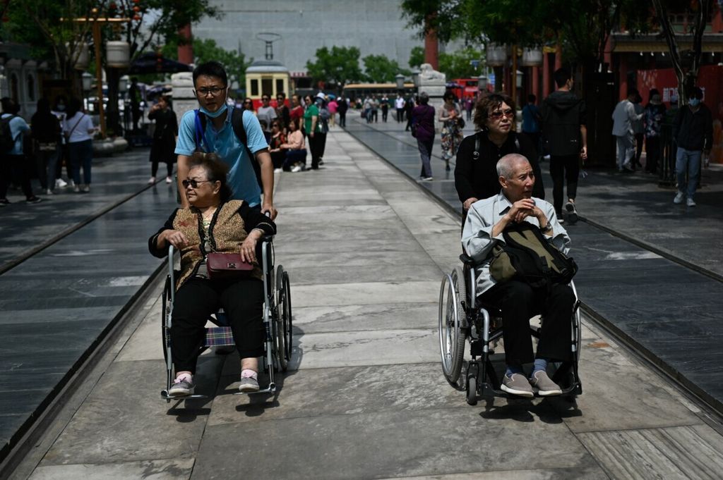Sepasang lansia di Beijing, China berjalan-jalan sambil didorong di atas kursi roda pada tanggal 11 Mei 2021.