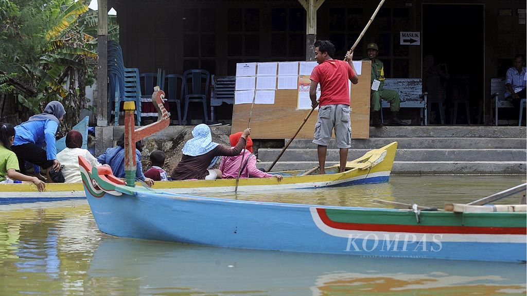 Untuk menyalurkan  hak pilih mereka, warga menggunakan perahu untuk menuju tempat pemungutan suara di Desa Mintobasuki, Kecamatan Gabus, Kabupaten Pati, Jawa Tengah, yang terendam banjir, Rabu (15/2). Permukiman warga dan lahan pertanian di kawasan itu sudah dua minggu  terendam banjir akibat luapan Sungai Silugonggo.