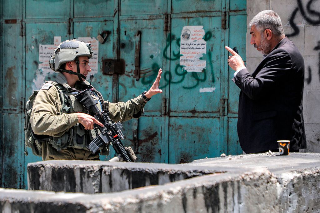 Seorang pria Palestina yang berdebat dengan anggota tentara Israel di pusat Hebron, Tepi Barat, Selasa (4/7/2023). Operasi militer Israel yang menduduki wilayah Tepi barat tersebut menyebabkan 10 warga Palestina tewas dan memaksa ribuan orang mengungsi. 